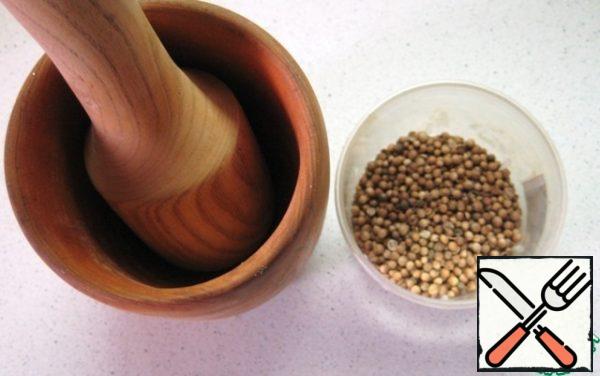 Coriander seeds are crushed and slightly crushed in a mortar.