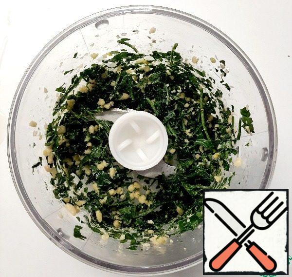 Place the washed and dried parsley without large stalks in the bowl of a blender. Add 2 tablespoons of pine nuts and a clove of garlic. Grind it.