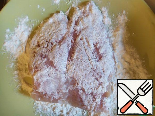 Pour the flour into a plate, roll the chicken in it on both sides.