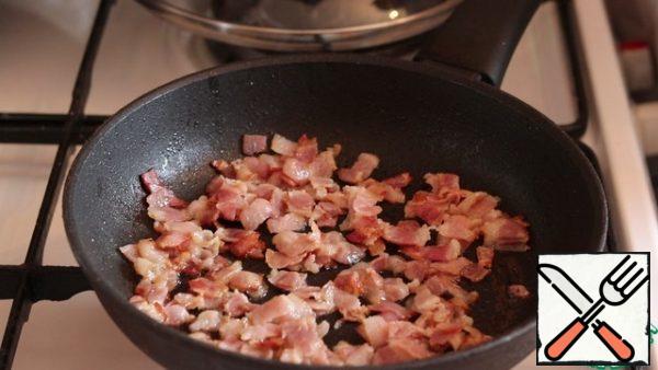 Cut the bacon into small pieces and fry in a preheated frying pan until golden brown.
