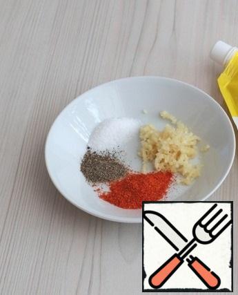 Prepare a spicy mixture for baking: In a bowl, add garlic (3 teeth) passed through a garlic press, add salt and ground black pepper to taste, add 1 teaspoon with a hill of sweet paprika. Mix the mixture.