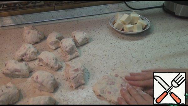 Divide the dough into 12 equal parts. Cut the cheese into 12 pieces. Take one piece of dough, mash it with your hands, put a piece of cheese and pinch the edges, forming a bun.