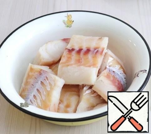 Fillet of cod, if it has been subjected to industrial glazing, defrost at room temperature, then lightly squeeze to remove excess liquid, cut into cubes. Add salt to the fillet, add ground white pepper to taste. Then add a mixture of spices for cooking fish and seafood. A mixture of spices can be made independently. It is specified in the ingredients.