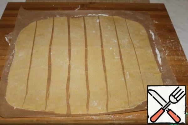 The second part of the dough is rolled out into a rectangular layer and cut into strips, 3.5-4 cm wide.