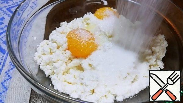 Previously, the yolks of 2 eggs are separated from the whites. In the cottage cheese, add 2 yolks, 60 g of sugar and about 30-35 g of semolina. Mix everything slightly.