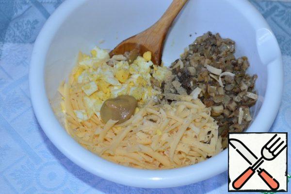 Hard-boiled eggs, peel and cut into cubes.
Add the fried onion and mushrooms, grated cheese (leave a little for sprinkling), mustard and spices. Mix thoroughly.