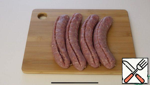 Using a spoon, we take out the minced meat from the sausages.