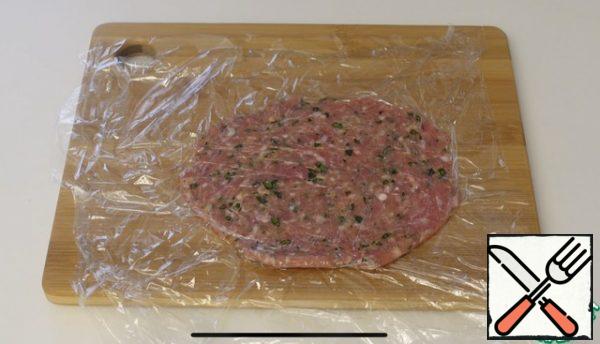Take 80 g of minced meat, cover on both sides with cling film, using a rolling pin, roll out the minced meat in a small circle.