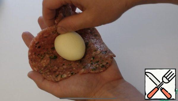 Lightly moisten your hands with water, take the minced meat, put an egg in the middle, wrap the minced meat, carefully shape it.