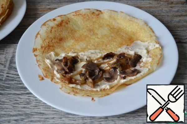 Half of the pancake spread with cheese, put the mushroom mixture.