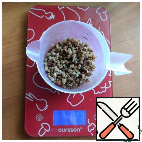 The first thing we need to do is cook buckwheat. We will need 100 g of boiled buckwheat in the dough. I have the weight on the scale along with the cup. It contains 20 g.