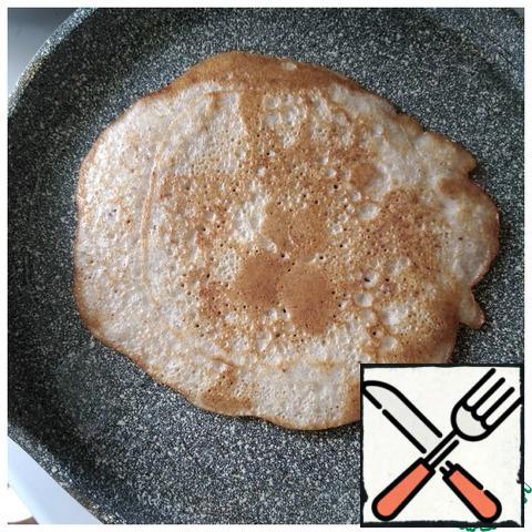 Bake the pancakes in a well-heated frying pan under a lid on both sides over medium heat, smearing it with refined sunflower oil (preferably a piece of lard) for each pancake.