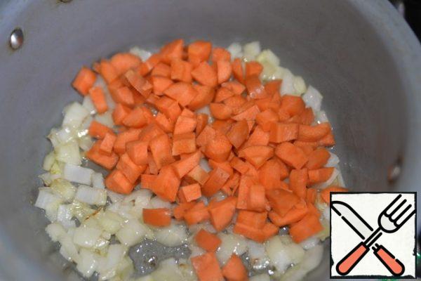 Onions and carrots are cleaned, cut into cubes. Take a saucepan or saucepan with a thick bottom, heat, pour the oil, fry the onion and carrot over medium heat for about 5 minutes.