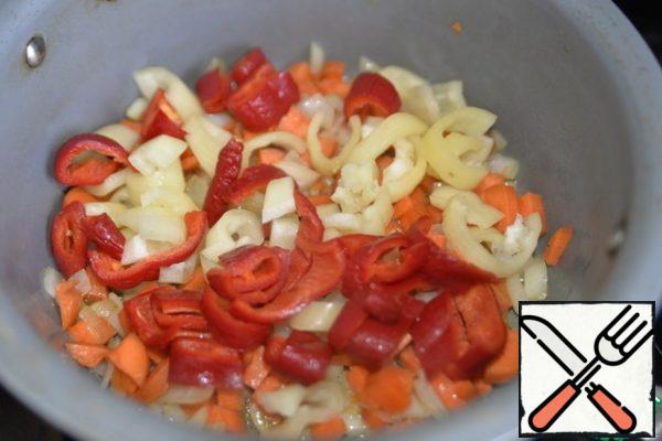 To the onion fried with carrots, put the chopped Bulgarian pepper and chili to taste. Stir and fry for 10 minutes over medium heat.