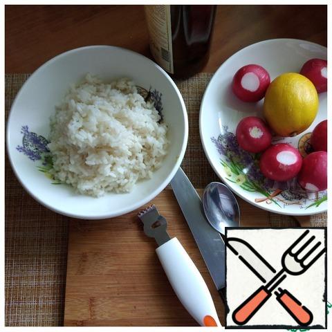 The rice is cooked. Straight hot rice spread in a salad bowl. We prepare radishes and lemon. The radish had small green sprouts and I left them to decorate the salad and cut a little into the salad.