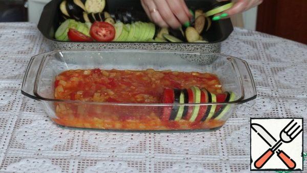 At the bottom of the refractory mold, spread the sauce from onions, tomatoes and peppers. Gently smooth it out. Add salt to the zucchini, tomatoes and eggplant. We put it in the form of alternating, putting it on the edge.
