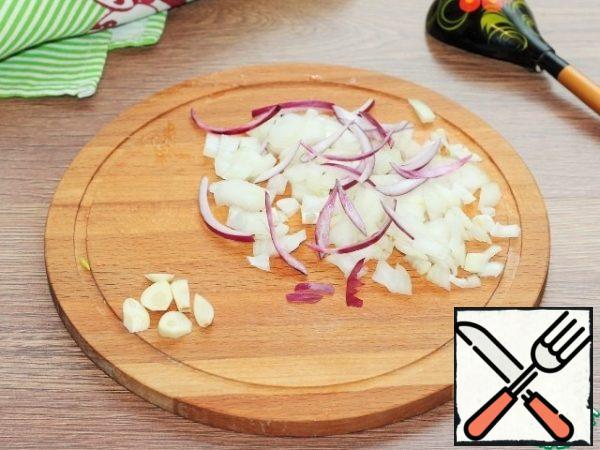 Cut the peeled onion and garlic into cubes and fry in preheated vegetable oil until transparent.