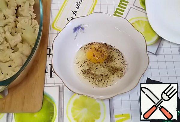 Prepare the filling.
Break the egg.
Add salt. Ground black pepper.
Mix lightly.