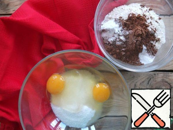 Before cooking, boil the kettle, we will need hot water.
the baking dish is covered with parchment and greased with oil. I baked in a slow cooker, but I put parchment on the bottom so that the sponge cake easily came out of the mold.
Sift the flour and cocoa powder into one container, add the baking soda and baking powder, and mix.
Beat the eggs, sugar and vanilla sugar until the sugar dissolves and increases in volume.
