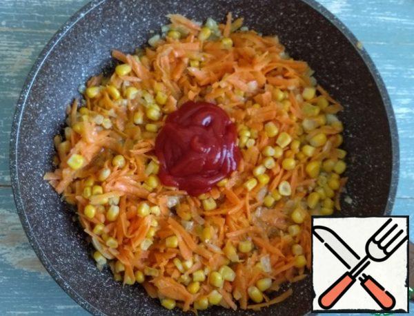Then add the carrots, grated on a coarse grater, canned corn and ketchup (or tomato paste). Fry for another 2-3 minutes.