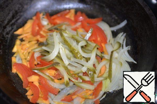 In a frying pan, pour vegetable oil and fry the vegetables until transparent over medium heat, then put the pickled cucumbers.