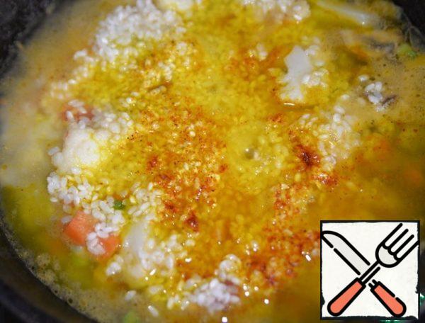 Pour boiling water or vegetable broth on top. Sprinkle with saffron. If you have saffron threads, I recommend that you soak them in warm water in advance. Bring to a boil and cook over low heat for 18 minutes. The rice should "gurgle" slightly.