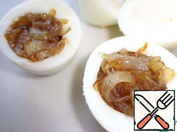 Clean the eggs, cut in half, remove the yolk. Cut off the bottom for stability, stuffed with fried onions.