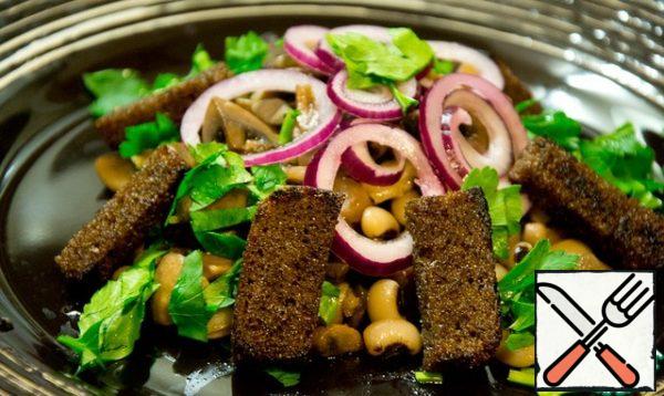 We collect the salad: on the mushrooms with beans, we put onions, croutons and sprinkle with herbs.