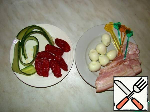 We will collect the necessary products.
Boil the quail eggs for 3 minutes, put them in cold water and cool them completely, clean them.
We spread the dried tomatoes on a paper towel to remove the excess olive oil.
Cut the cucumber into long strips with a paring knife.