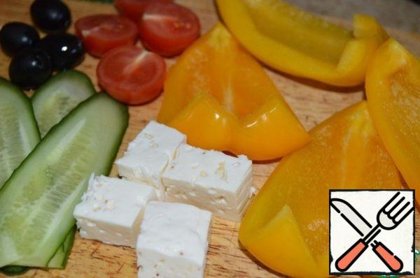 Cut the pepper into four parts, remove the seeds and stalk. Cut the tomatoes in half. Cut the feta or cheese into cubes. Can cut cut diagonally into thin long ovals.