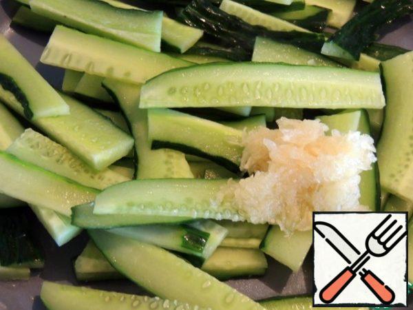 Cucumber cut into plates. In a heated frying pan with vegetable oil, send the cucumber and garlic. Mix it up.