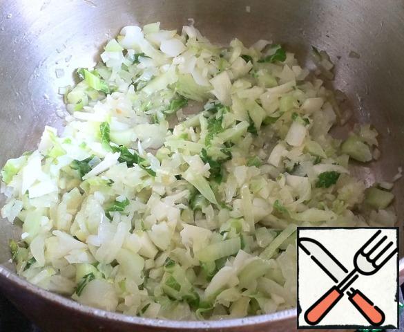 The size of the pot in which you will cook should be slightly larger than the size of a fork of cabbage.
Pour in 1 tablespoon of olive oil and fry the onion, garlic and the stem with the leaves until soft.