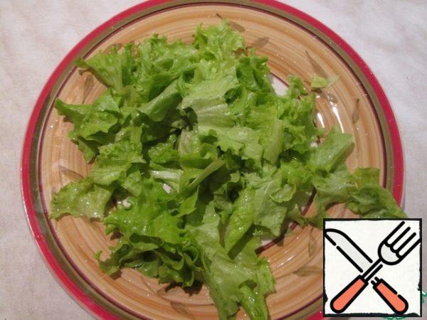 Prepare the dressing: mix the olive oil, juice of 1/2 lemon, salt and pepper. Tear the lettuce leaves with your hands, put them on a serving plate and pour half of the dressing over them.