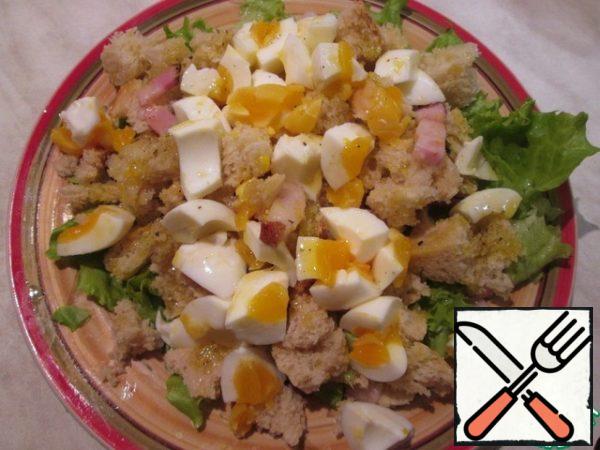 On the lettuce leaves, spread warm crackers with bacon, on top-coarsely chopped eggs, pour the remaining dressing. You can sprinkle with cheese. The salad is ready!