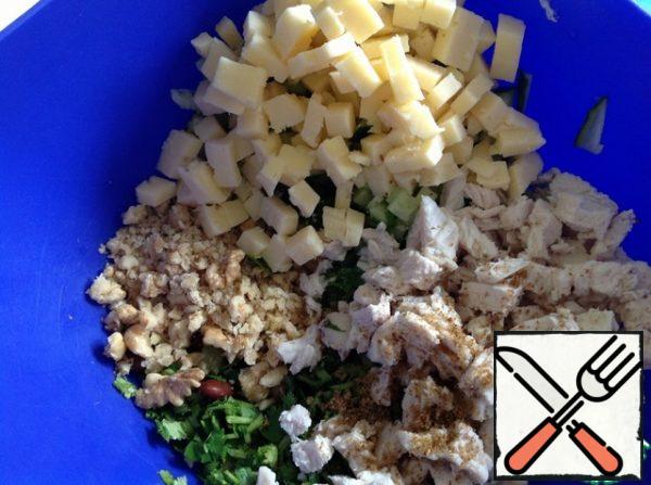 Cheese and boiled chicken breast cut into small cubes.
Nuts are rolled with a rolling pin, not very finely.
Add salt, adjika and hops-suneli.