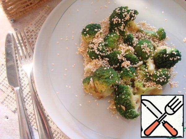 Broccoli spread on a plate, pour the dressing. She absorbed it well. Sprinkle with toasted sesame seeds.
