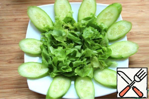 Cut the cucumbers diagonally, and the cherry into circles. Tear the lettuce leaves or cut them into strips.
Spread on a salad bowl, in the middle, lettuce leaves.
Spread cucumbers around the lettuce leaves.
