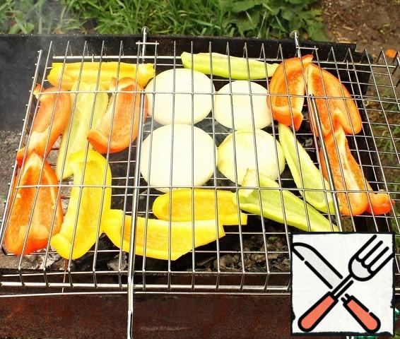 Cut the peeled onion into medium rings. Cut the washed and dried pepper in half, remove the seeds and stalks and cut into plates. Spread the onion and pepper on the grill and bake until tender.