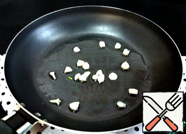 In a frying pan, heat the vegetable oil over medium heat. Add the garlic, cut into slices, and heat it for a minute.