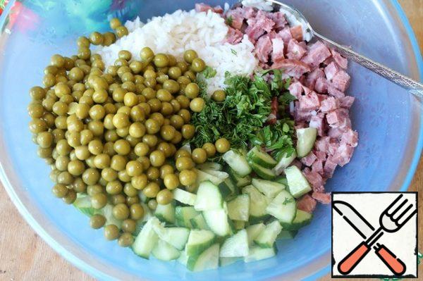In a deep bowl, combine the washed rice, diced sausage, cucumber, herbs and peas.