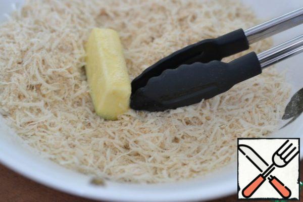 Mix the breadcrumbs and grated cheese.
Roll the zucchini pieces in the mixture.