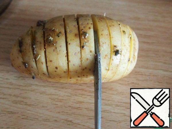 Now, using the handle of a teaspoon, fill each cut with the sauce. Just type a little oil-herb mixture on the tip and lubricate the incision with it. You can use a silicone brush, but there is a risk of breaking the potato.