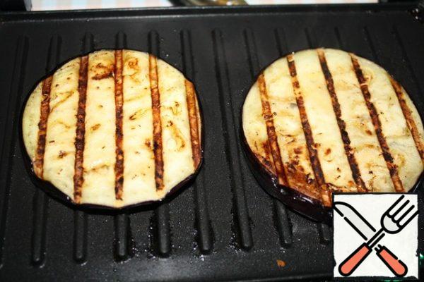 Eggplant should be cut into thick washers, about a centimeter thick. Add salt and let sit for 20 minutes. Then rinse and squeeze.
There are two cooking options.
The first is to fry the slices in oil.
The second is to bake on the grill.
I baked my own on an electric grill, lightly drizzled with oil.