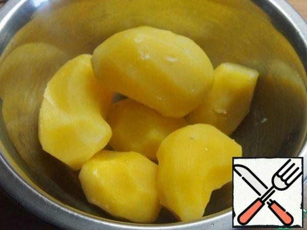 Peel the potatoes and cook them whole in salted water until tender, but do not boil them. Cool down.