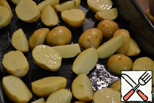 Grease the prepared baking dish with sunflower oil.
Wash and dry the potatoes.
Cut the potatoes in half, and if large, then into quarters. We spread the potatoes in the form. Add salt and mix well.