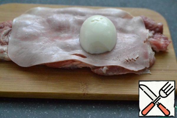 Cover the chipped piece of meat with a plate of ham along the entire length.
Put half an egg on one half.