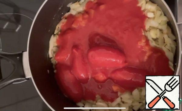 Then add the tomatoes in their own juice and crush them, let them boil slightly, put a spoonful of sugar, salt, and black pepper, white wine, tomato paste