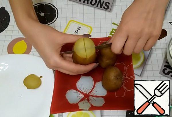 Potatoes should be placed in a plate vertically.
We cut off the tops of each potato.
We make a cross-shaped incision.