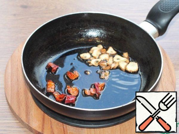 In the heated vegetable oil (3 tbsp. l.), fry the hot pepper and garlic cut into slices. Then we remove the vegetables, leave the oil.