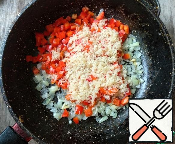 Add rice and pepper to the onion and garlic, add salt (1 tsp) and fry for another 5-7 minutes.